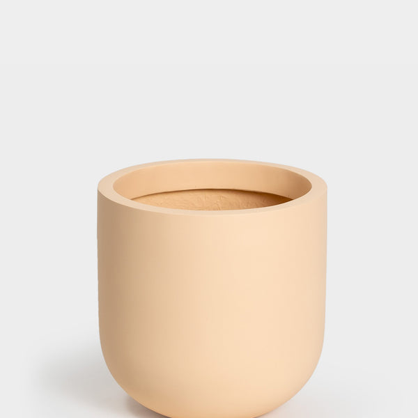 A simple, beige, round ceramic planter with smooth matte finish, set against a plain light gray background. The planter has a wide opening and no visible designs or patterns.